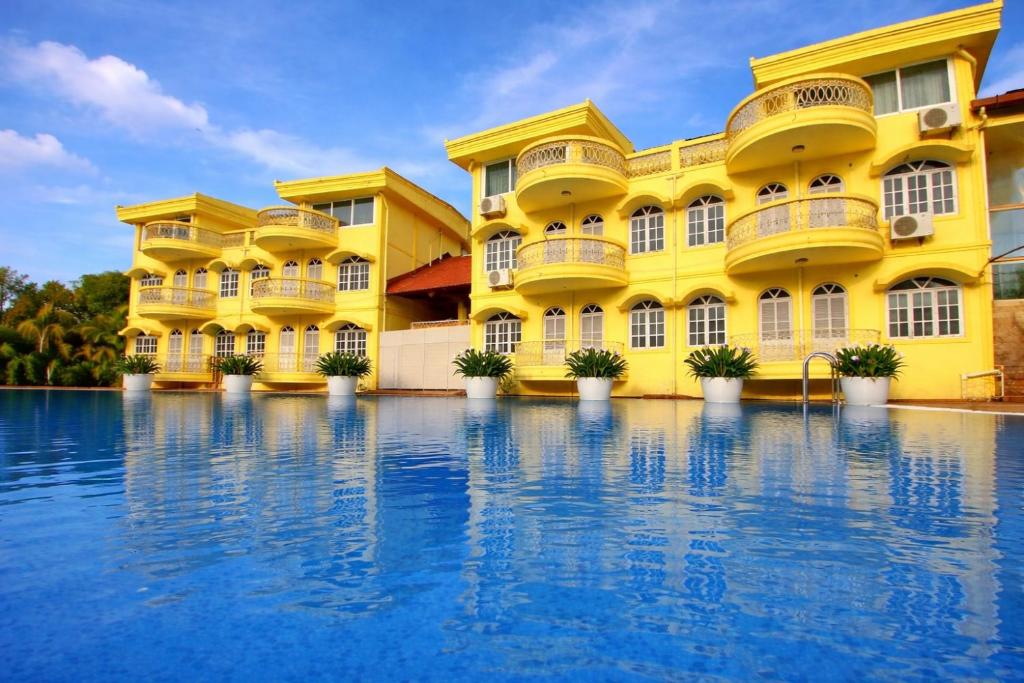 a yellow building with a pool in front of it at Praia Da Oura Boutique Resort ,Goa in Majorda