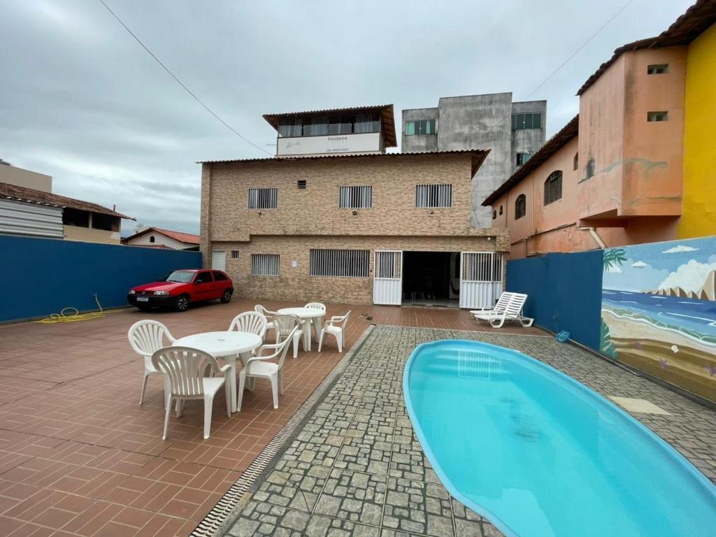 a patio with tables and chairs and a swimming pool at Pousada Mirante do Sol in Piúma
