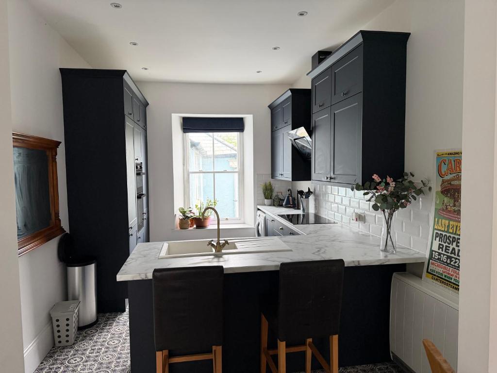 a kitchen with black cabinets and a white counter top at The Teign Rooms in Teignmouth