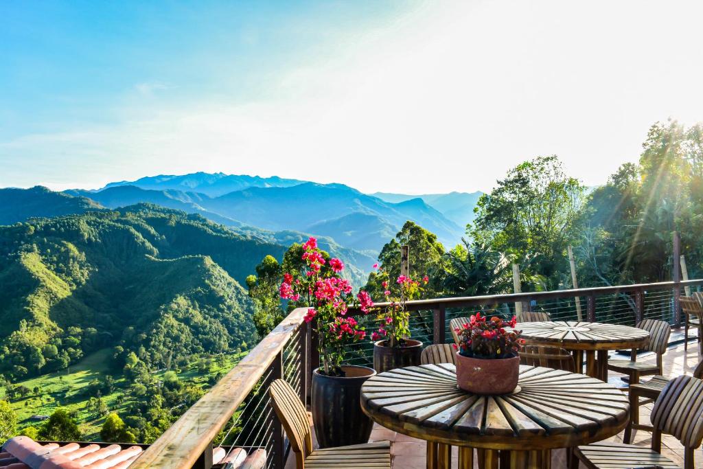 a balcony with tables and chairs and a view of mountains at Canela Mountain Villa Hotel in Salento