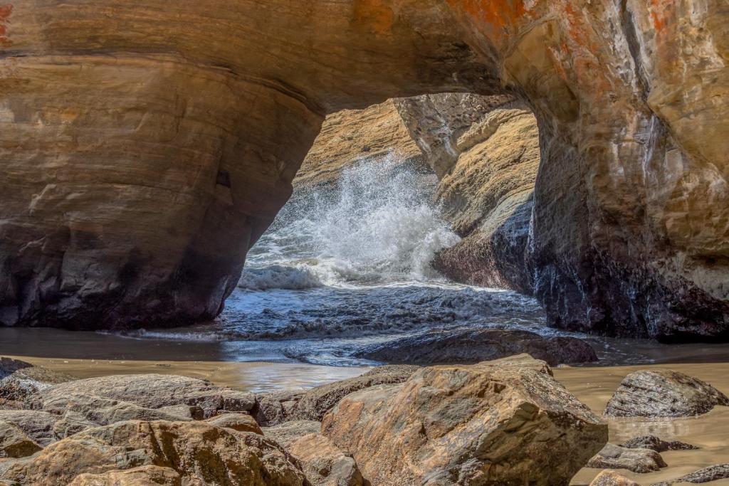 a view of a waterfall from a rock cave at Fun Times At Nye Beach in Newport