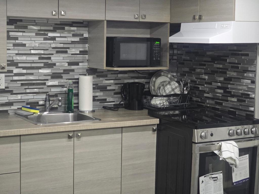 a kitchen with a sink and a microwave at Comfortable Stay Evanston NW - Near YYC Airport, Highways, Shopping & Parks in Calgary