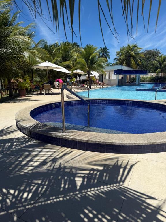 a swimming pool with palm trees in the background at Paraiso dos coqueiros - Guarajuba - Bahia -Linha verde in Camaçari
