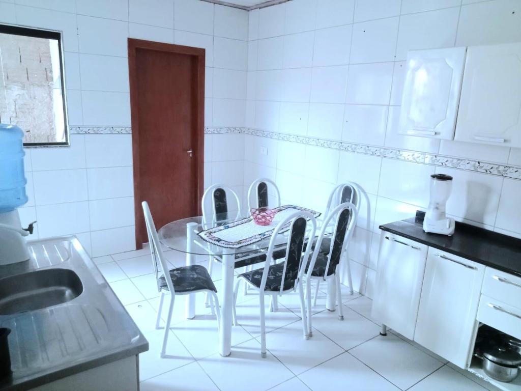 a white kitchen with a table and chairs in it at Ambiente familiar em Poços de caldas in Poços de Caldas