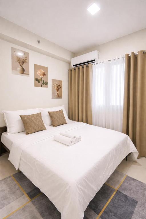 a bedroom with a large white bed with a window at Casa MJ Suites at SMDC Fame Residences, Mandaluyong in Manila