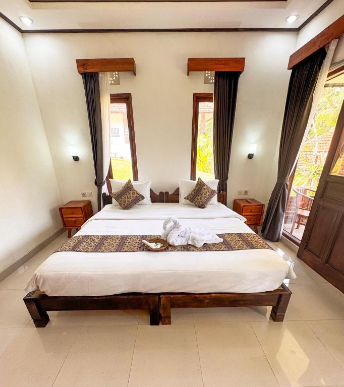 a bedroom with a large bed in a room with windows at Indra Yoga Retreat in Selemadeg