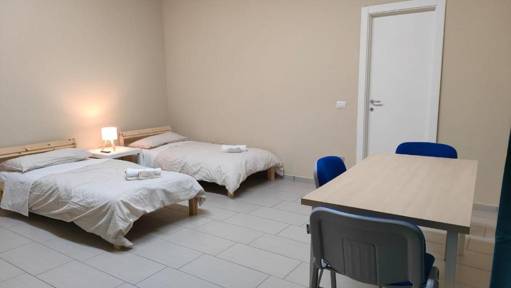 a room with two beds and a table and chairs at Camera doppia in San Giuseppe Vesuviano