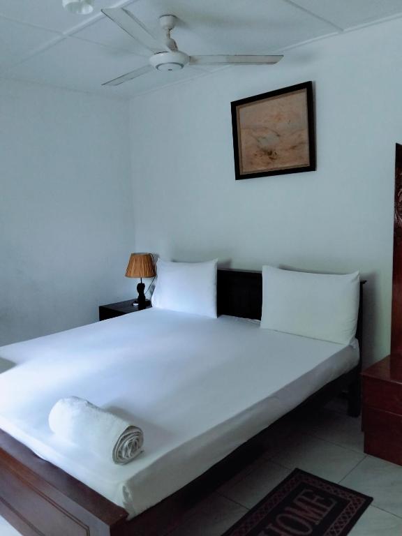 a bedroom with a bed with white sheets and a ceiling at New Villa Senor Beruwala in Beruwala