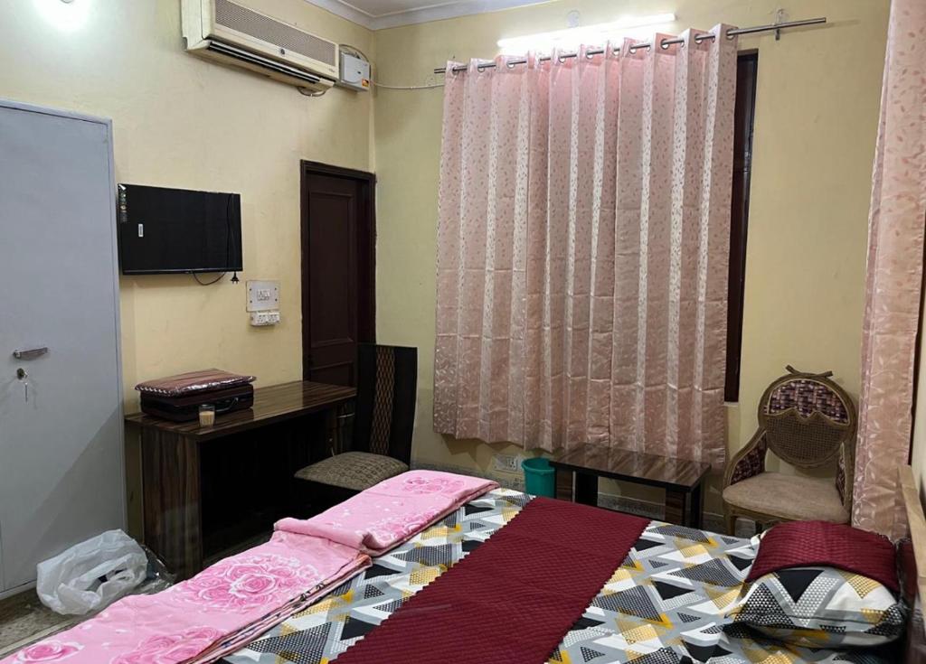 a bedroom with a bed and a desk and a window at Metro 21 in Faridabad