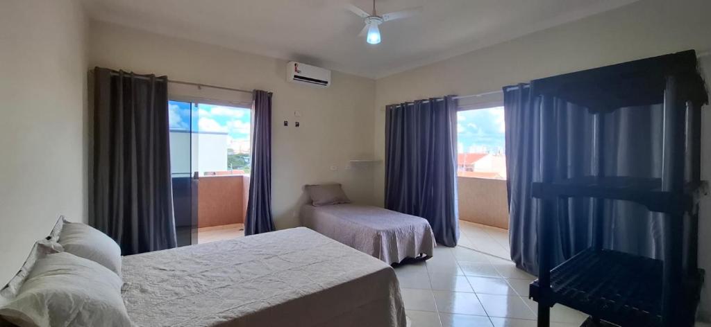 a bedroom with a bed and a chair and a window at SOBRADO - ótimo custo beneficio - 3 quartos com ar in Campo Grande