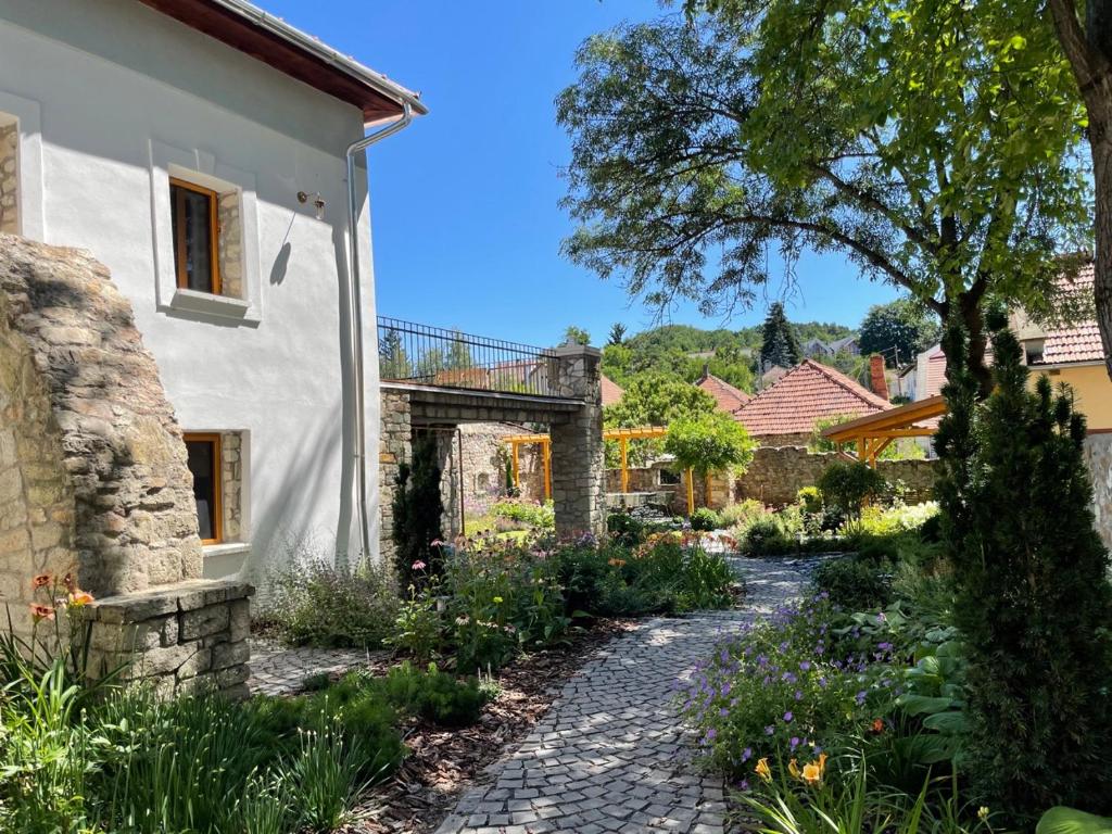 a garden with a stone walkway next to a white house at TR 1823 Vendégház in Mád