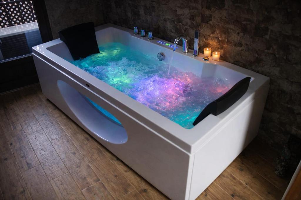 a white bath tub with a purple and blue water at Casa Rural Casa de Chocolate in Cuevas del Valle