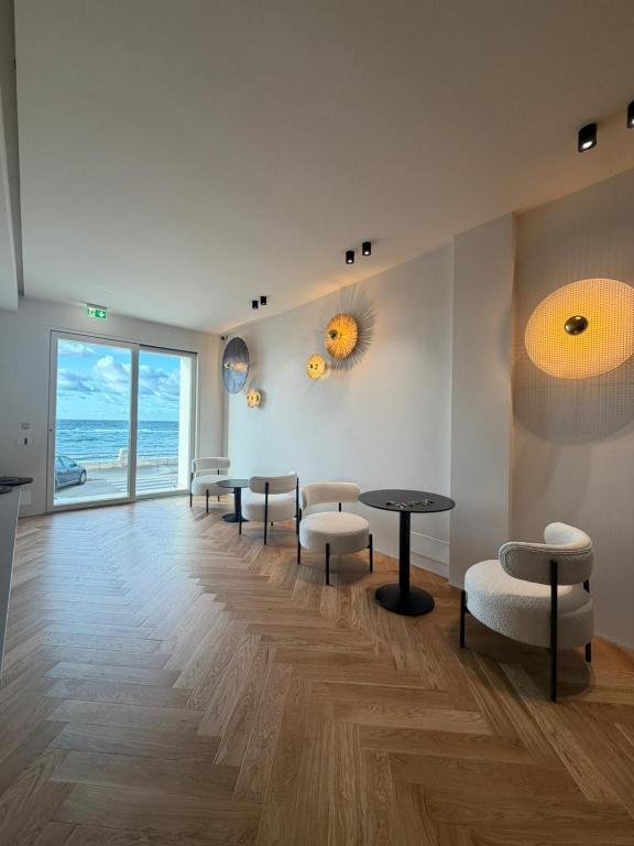 a waiting room with tables and chairs and the ocean at Rumare - BADIA NUOVA in Trapani
