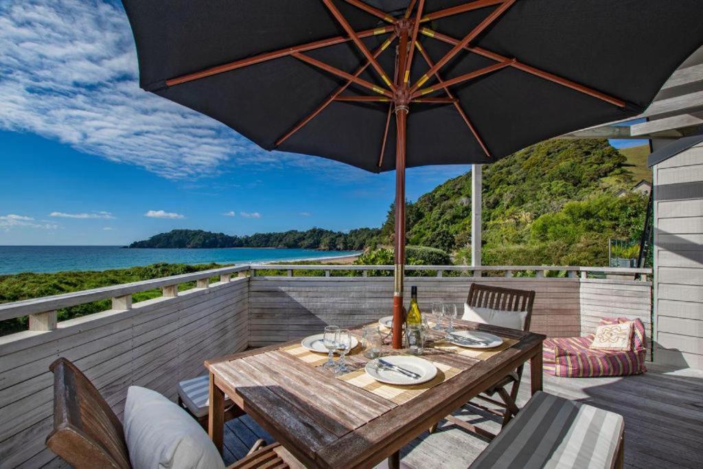 a wooden table with an umbrella on a deck at Spectacular Woolleys Bay in Matapouri