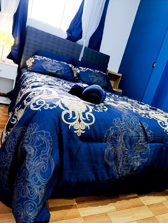 a blue bed with a blue and white comforter at Unique garden deluxe apartment in Trujillo
