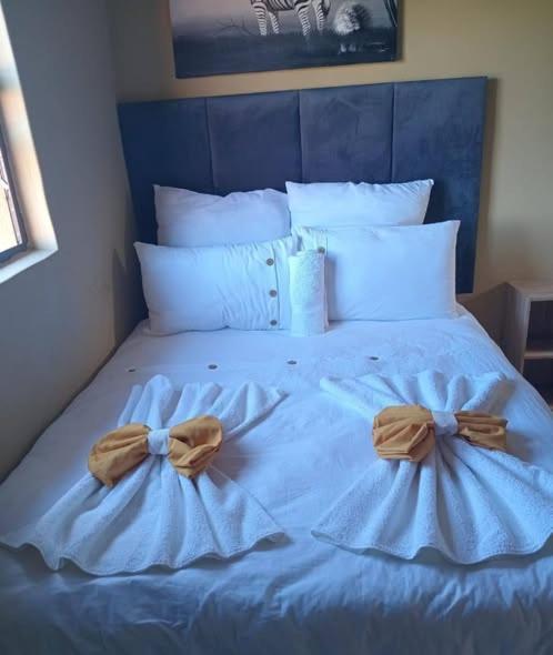 a bed with blue sheets with bows on it at Cozy Road Lodge in Sihangwane