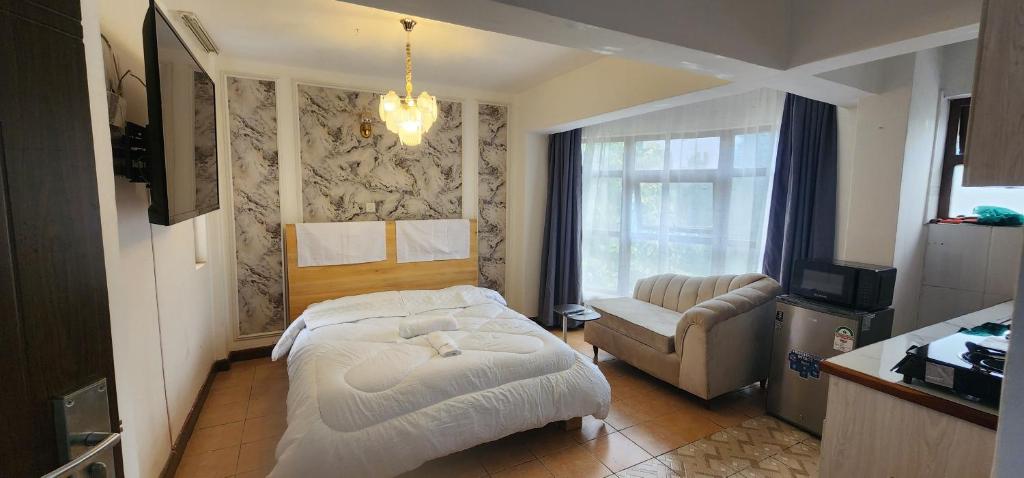 a room with a bed and a chair and a television at Emeli apartments in Nairobi