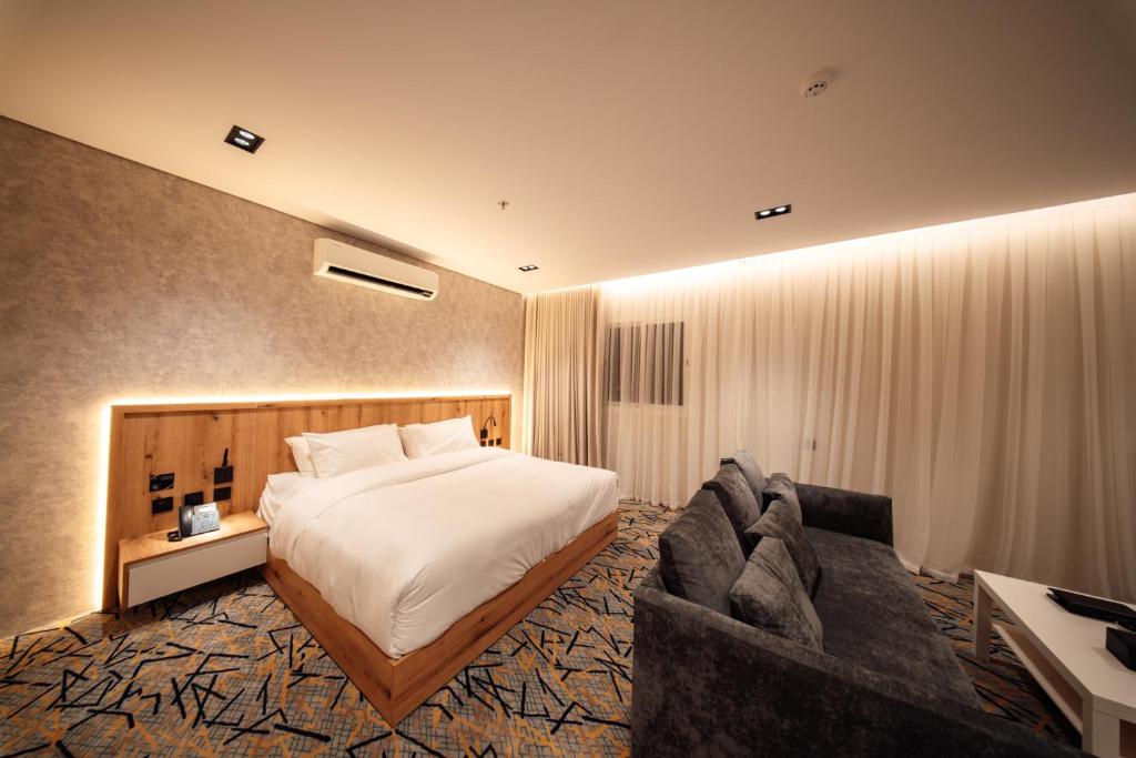 Aurion Al-Aqeeq Hotel في المدينة المنورة: غرفة فندق بها سرير وأريكة