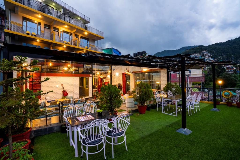 a patio with white chairs and tables and a building at PACK Mcleodganj in McLeod Ganj