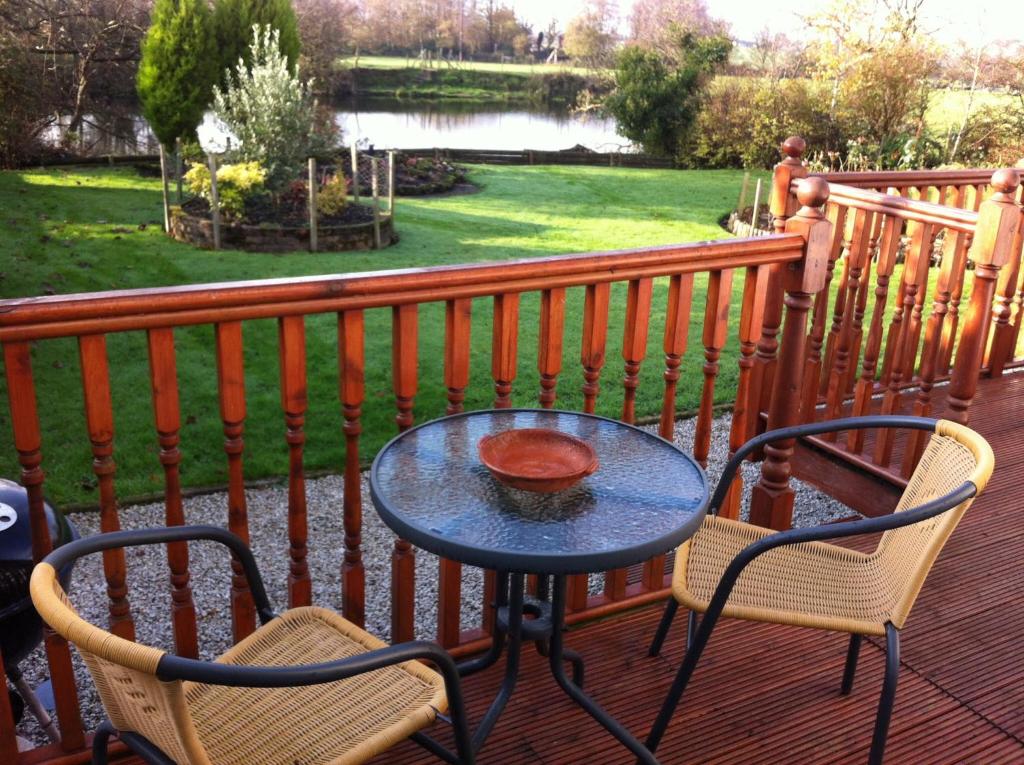 a table and chairs on a deck with a view of a park at Merok Lodge in Great Eccleston