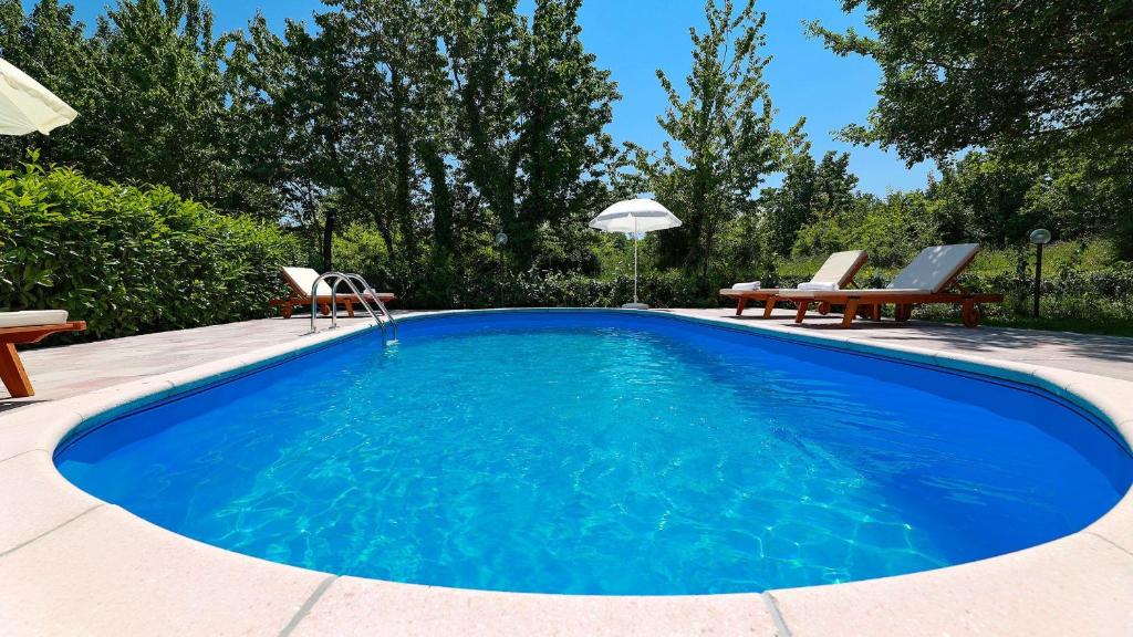 a swimming pool with two chairs and a table at Apartments Sonja in Šilo