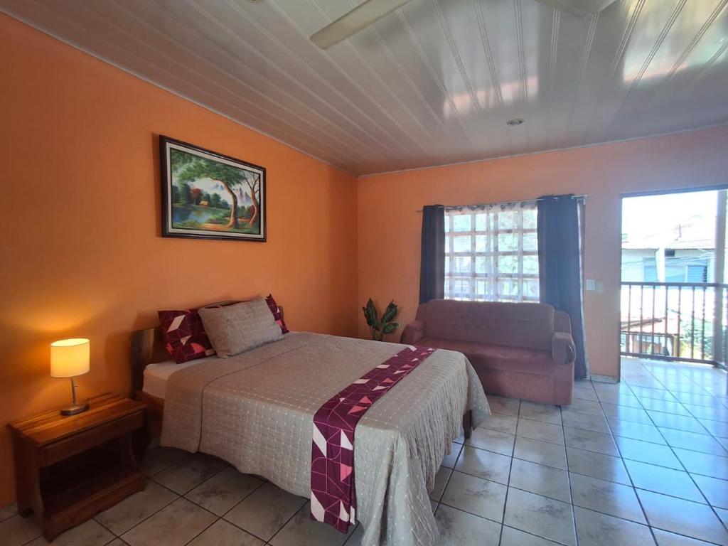a bedroom with a bed and a couch and a window at Quepos Studio Apartments in Quepos