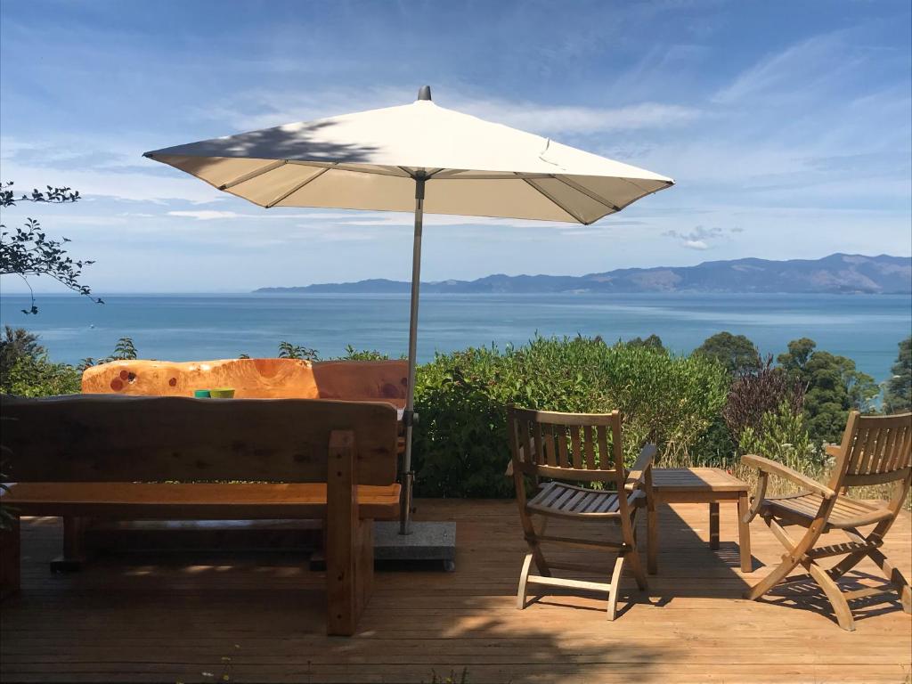 a patio with a table and an umbrella and chairs at Ao Marama Retreat in Collingwood