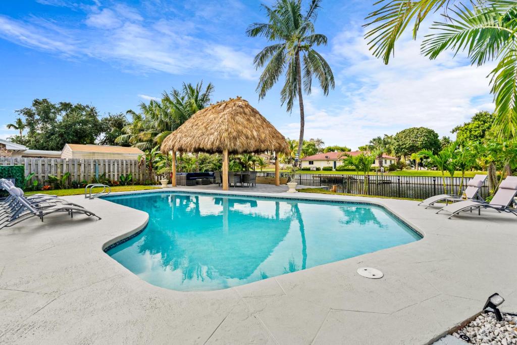 a swimming pool with chairs and a straw umbrella at Waterfront Oasis, Heated Pool, MiniGolf, TikiHut in Lake Clarke Shores