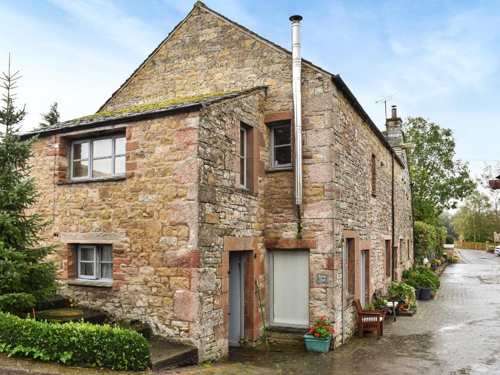 an old brick house with a white door at Barn End in Pooley Bridge