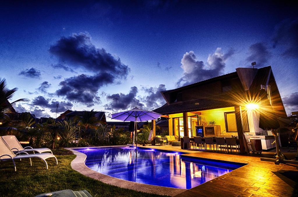 - une piscine en face d'une maison la nuit dans l'établissement Novo Bangalô no Malawi Beach House com Premium Service, à Porto de Galinhas