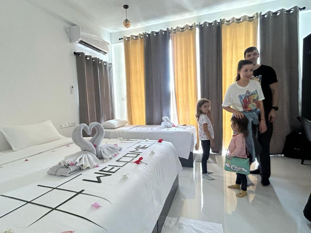 a man and a woman and two children standing in a bedroom at REEF SHINE Thoddoo in Thoddoo