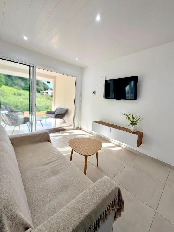 a living room with a couch and a tv at Le Cocon du Cos in Ducos