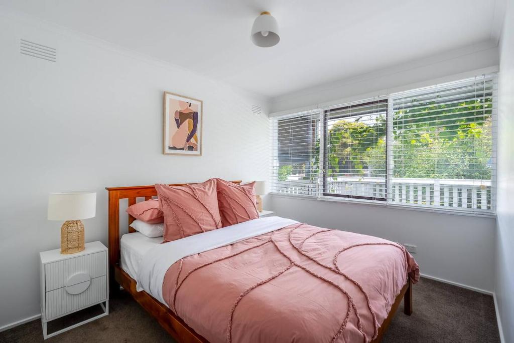 a bedroom with a bed with pink sheets and a window at 550m to Beach, SPA and Large Backyard , Sleep 9 in Ocean Grove
