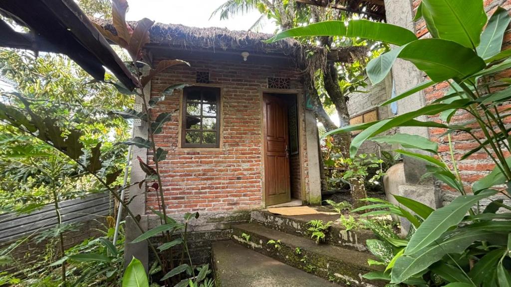a brick house with a door in a garden at Nostalgia Camping Home in Selemadeg