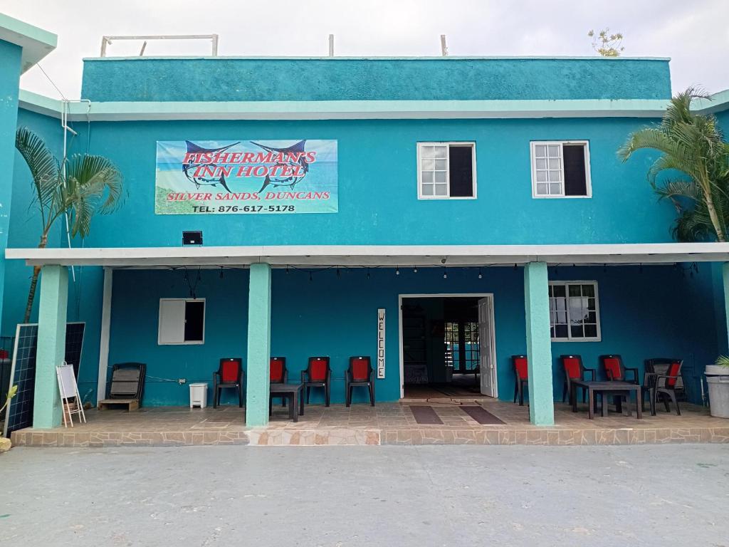 a blue building with red chairs in front of it at Fisherman's Inn Hotel Silver Sands, Duncans Bay in Duncans