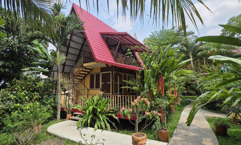 a house with a red roof in a garden at Mekong Delta Ricefield Lodge in Can Tho