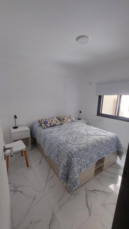 a white bedroom with a bed and a window at Arena Studio Mar de Ajó in Mar de Ajó