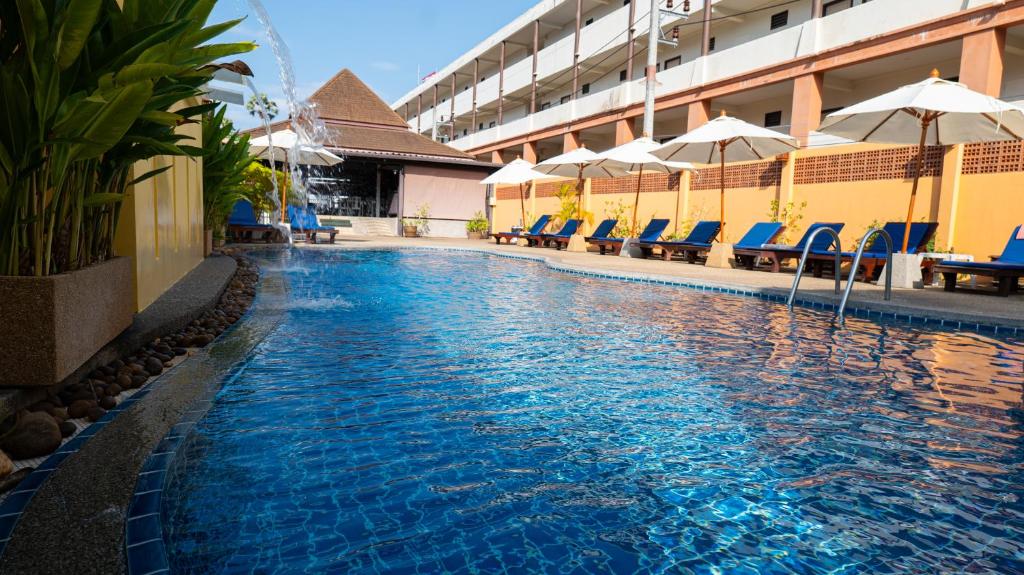 a swimming pool with chairs and umbrellas in a hotel at Kata Silver Sand in Kata Beach