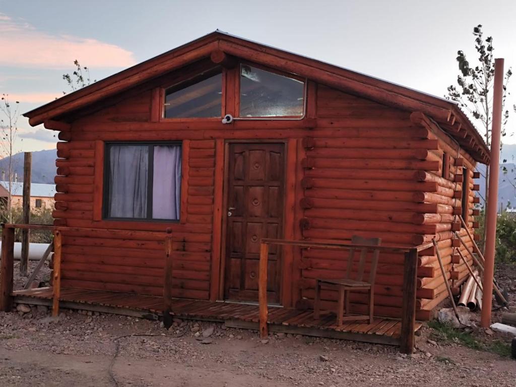 a small log cabin with a door and a chair at Cabañas Paraje de los Sueños in Uspallata