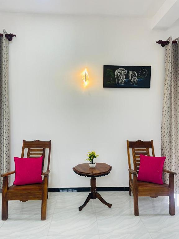 a room with two chairs and a table with pink pillows at Nithuki Villa Weligama in Weligama