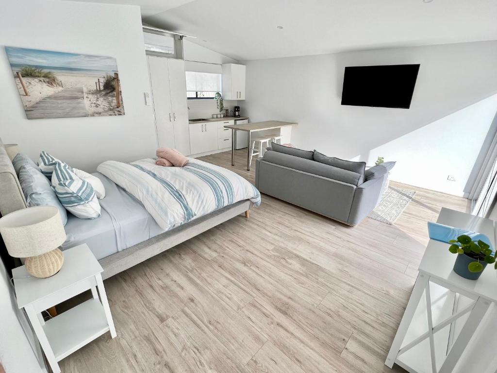 a bedroom with a bed and a couch and a television at Private Barwon Heads Cottage Walk to River in Barwon Heads