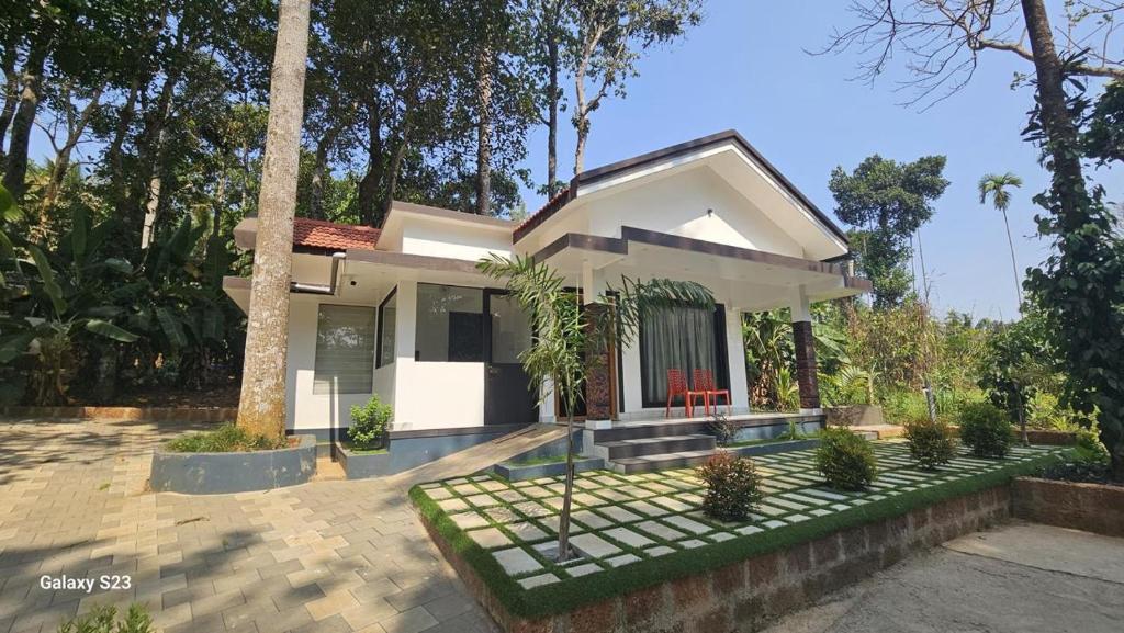 a small white house with a palm tree at Green Leaf in Padinjarathara