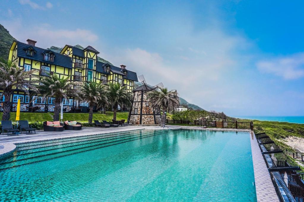 a swimming pool in front of a building with the ocean at Stuart Villa in Yanliau