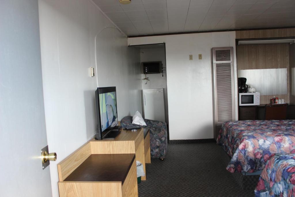 a hotel room with a room with a bed and a television at Raval Paradise Motel and RV Park in Youngstown