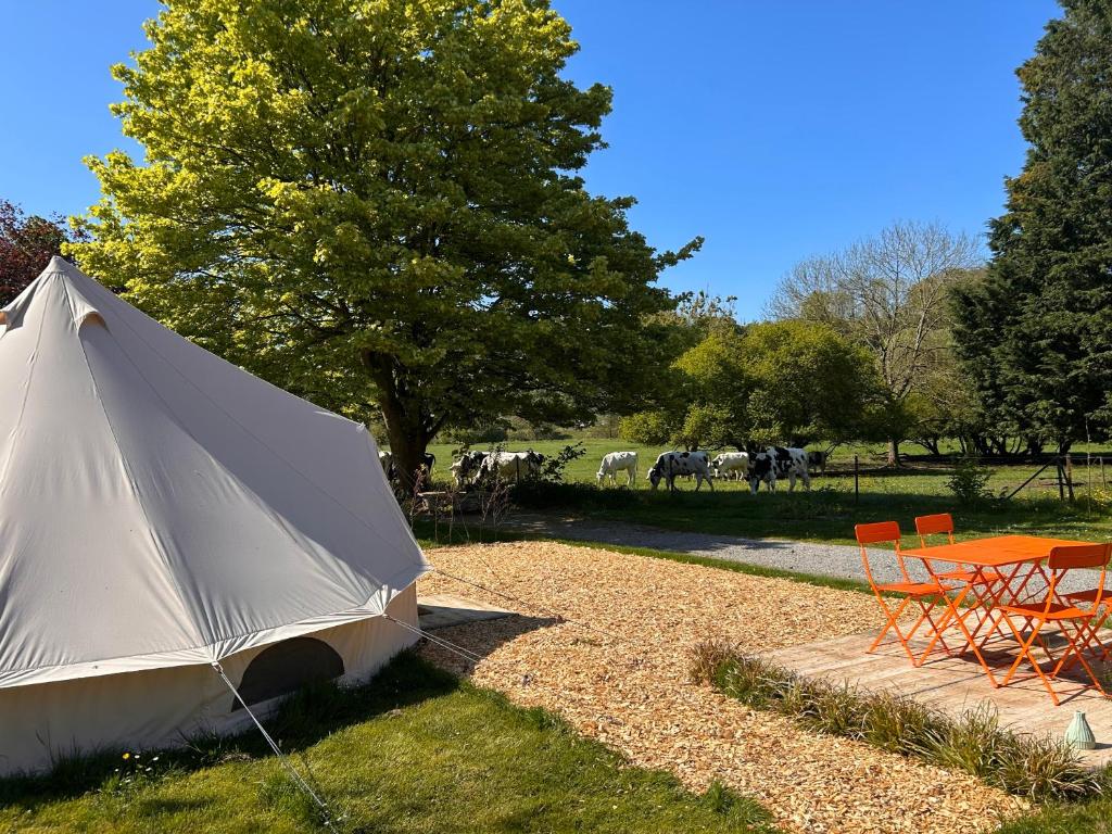 a white tent sitting in the grass with a table and chairs at Glamping Les Arpents Verts in Yvoir
