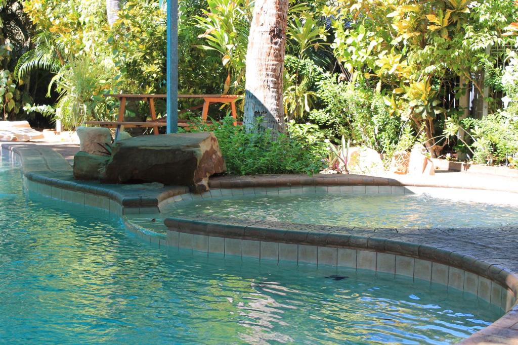 una piscina de agua con un banco en el medio en Roey Backpackers and Party Bar en Broome