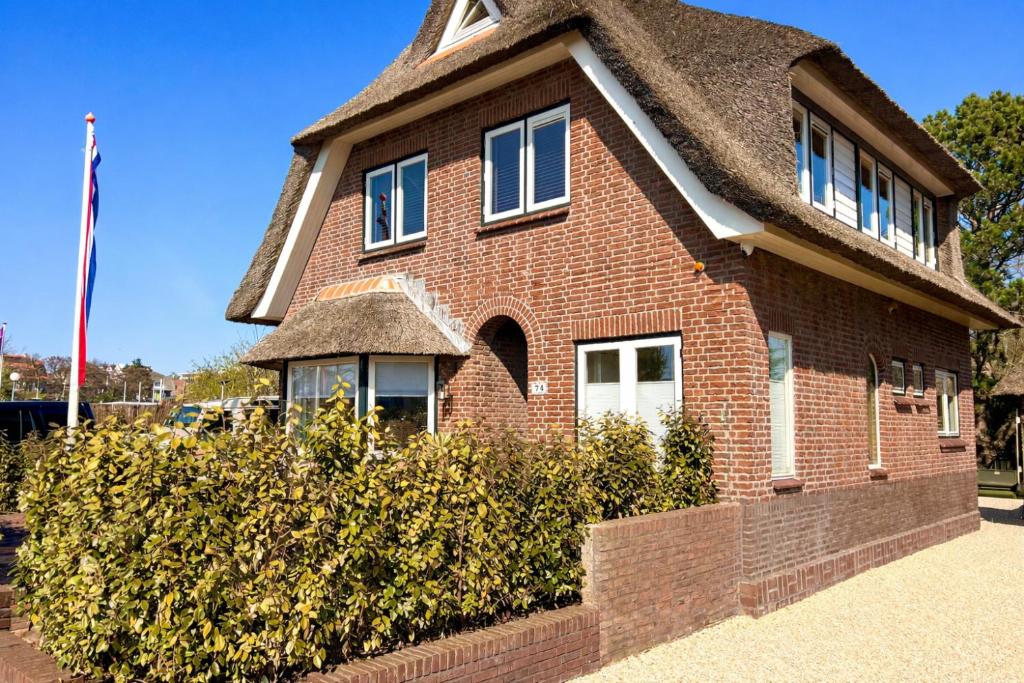 a red brick house with a thatched roof at Villa Verano in Noordwijk aan Zee