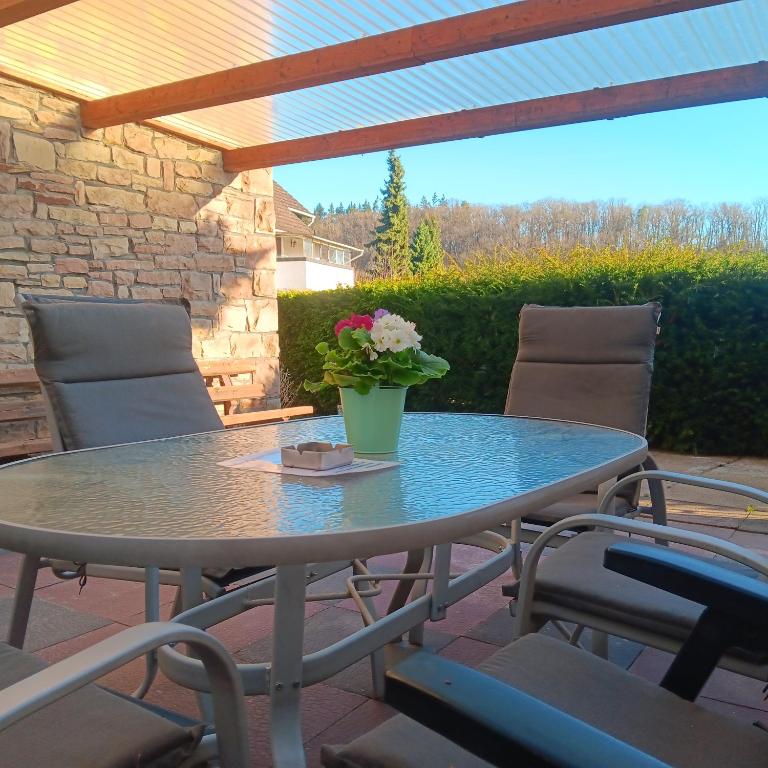 a table with a vase of flowers on a patio at Haus Eifelglück am Stausee Obermaubach in Kreuzau