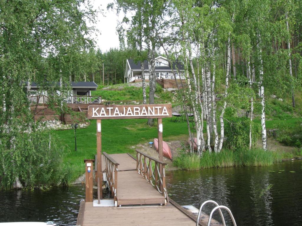 un muelle de madera con un cartel en la parte superior de un lago en Katajaranta, en Enonkoski