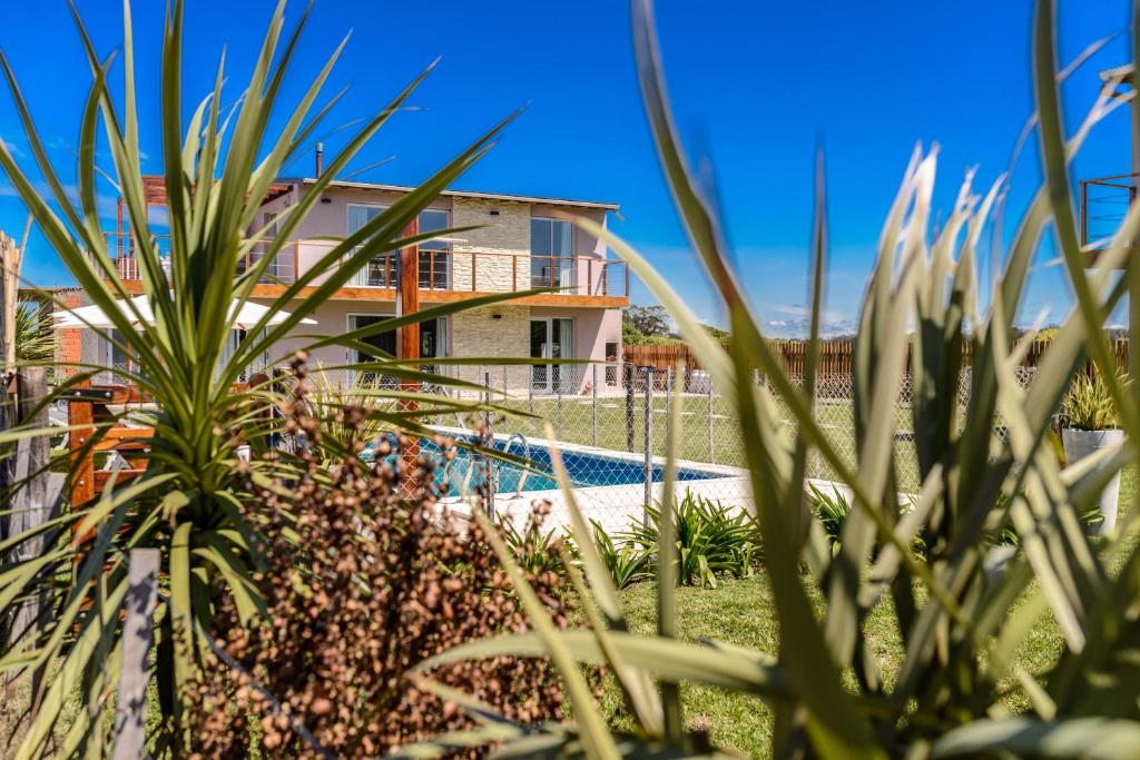 a villa with a swimming pool in front of a house at Radazul Apart de Mar & Campo in Chapadmalal